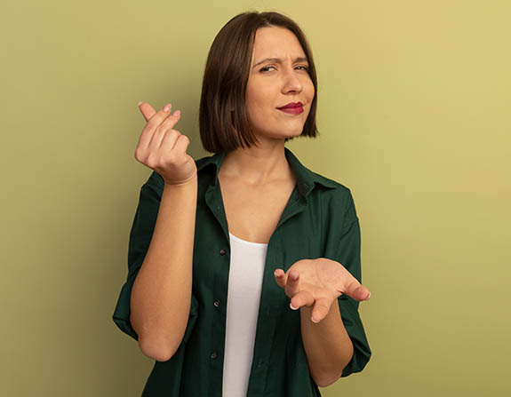 jade advocacia_0007_confident-pretty-caucasian-woman-holds-hand-open-gestures-money-hand-sign-olive-green