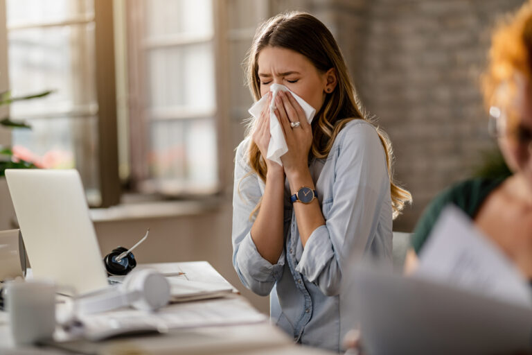 Young businesswoman using a tissue while sneezing in the office