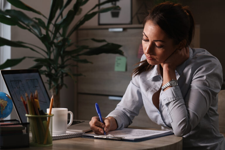 Young businesswoman feeling bored while filling out paperwork in